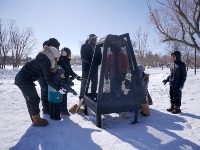 People bundled up and gathered around a community fire pit.