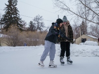 Two people enjoying a leisurely skate on an outdoor rink.